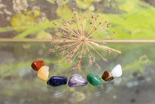 Sieben verschiedene Heilsteine nebeneinander arrangiert.